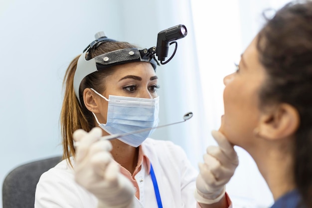 Vrouwelijke patiënt die haar mond opent zodat de dokter in haar keel kan kijken Otolaryngoloog onderzoekt keelpijn van patiënt