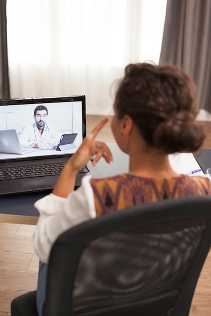 Foto vrouwelijke patiënt in een videogesprek met arts die over haar medicijn praat.