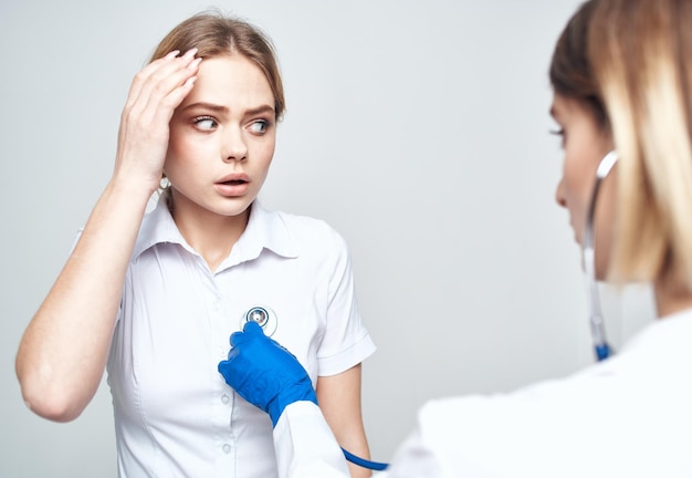 Vrouwelijke patiënt klaagt over hoofdpijn bij arts met stethoscoop
