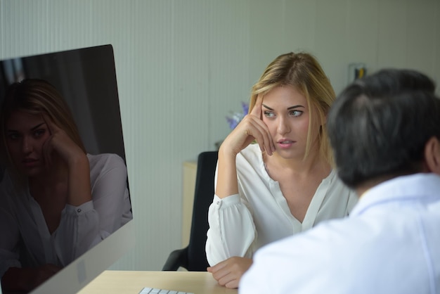 Foto vrouwelijke patiënt met arts die in de computermonitor in de kliniek kijkt