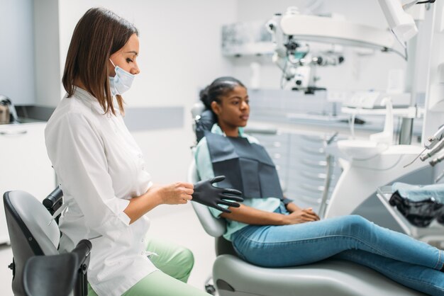 Vrouwelijke patiënt op stoel en tandarts, bezoek in tandheelkundige kliniek.