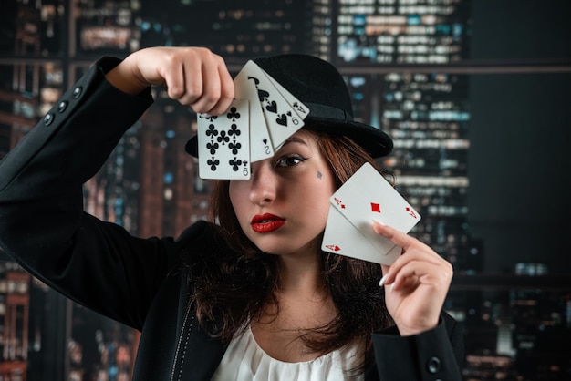 Vrouwelijke pokerspeler prachtig gekleed met exquise parfum met kaarten in handen aan de casinotafel