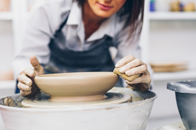 Vrouwelijke pottenbakker die aardewerk van klei op een spinwiel maakt.