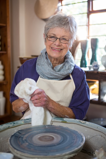 Vrouwelijke pottenbakker die haar hand met servet afveegt