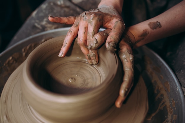 Vrouwelijke pottenbakker die kleiaardewerk op een spinwiel maakt.