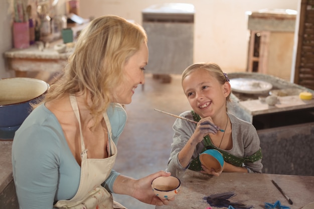 Vrouwelijke pottenbakker die met meisje in aardewerkworkshop interactie aangaan