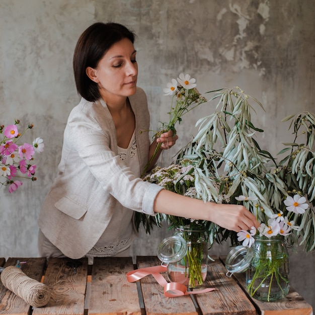 Vrouwelijke professionele bloemist bereidt de opstelling van wilde bloemen voor.