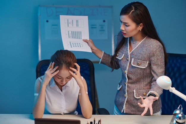 Vrouwelijke projectmanager vertelt UI-ontwerper voor slecht werk wanneer ze 's avonds laat op kantoor blijft voor de deadline