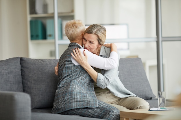 Vrouwelijke psycholoog troost volwassen vrouw in therapie sessie