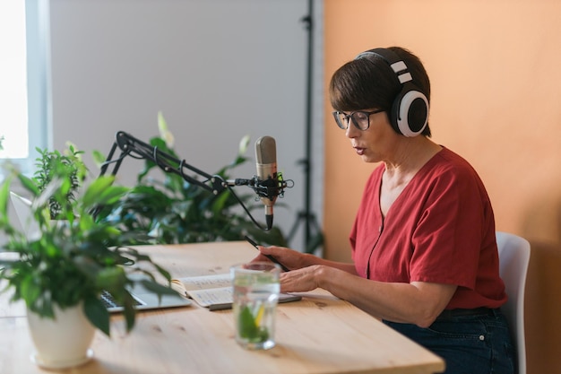 Vrouwelijke radiopresentator van middelbare leeftijd die in de microfoon praat en nieuws leest - radio-uitzending online conceptpersoon