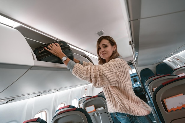 Vrouwelijke reiziger die tijdens het instappen bagage in de bagageruimte van het vliegtuig stopt