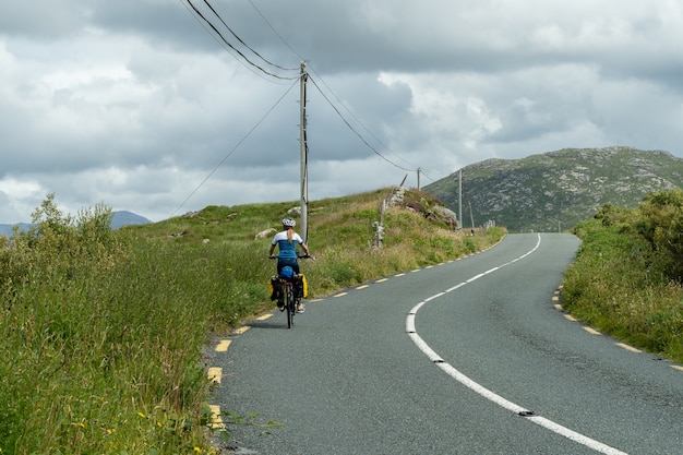 Vrouwelijke reiziger wielrenner trappen in het bergachtige landschap van Connemara Galway, Ierland