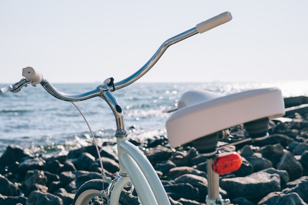 Vrouwelijke retro fiets op het strand met blauwe zee op zonnige dag