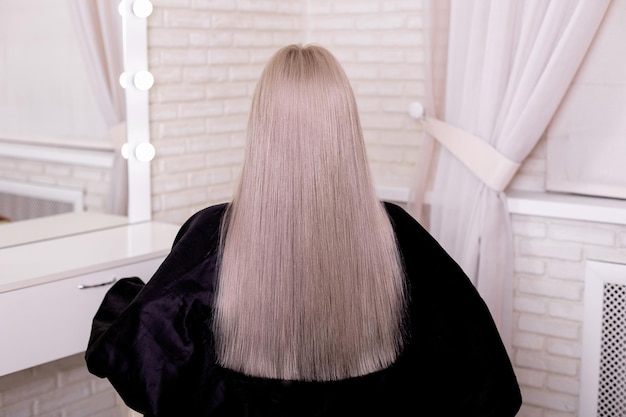 Vrouwelijke rug met lang recht blond haar in een kapsalon