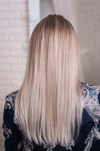 Vrouwelijke rug met lang recht blond haar in een kapsalon