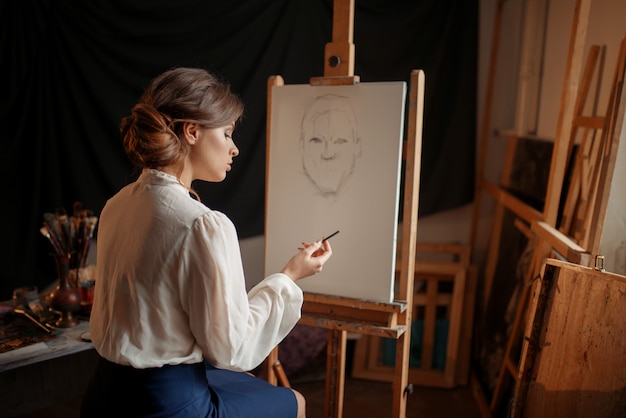 Vrouwelijke schilder in studio, potloodschets op ezel. creatieve verf, vrouw portret tekenen, workshop interieur op achtergrond