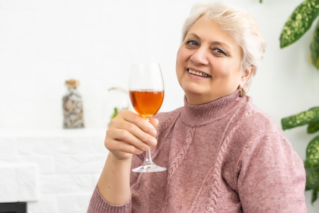 Vrouwelijke senior drinken van rode wijn - geïsoleerd op een witte achtergrond.