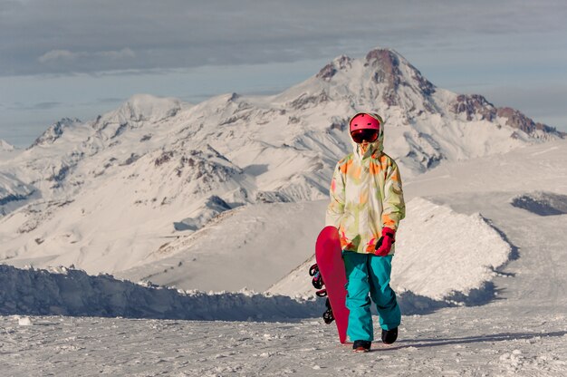 Vrouwelijke snowboarder in sportkleding lopen op bergtoppen