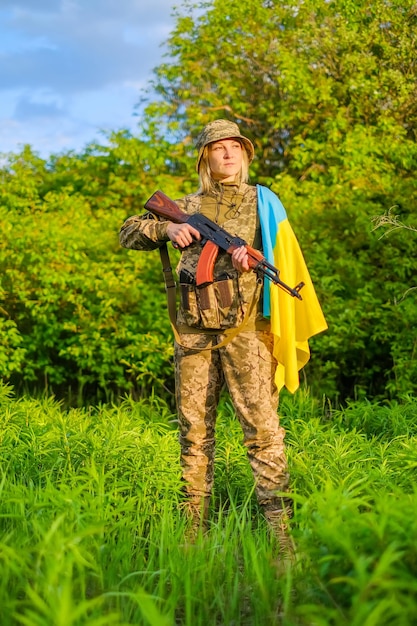 Vrouwelijke soldaat met een pistool en Oekraïense vlag op de schouder die wegkijkt