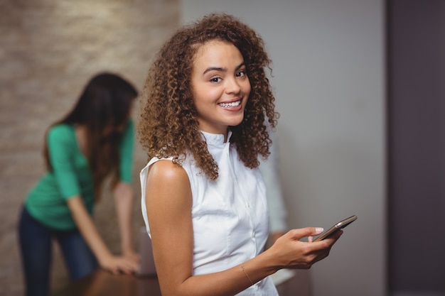 Vrouwelijke stafmedewerker die digitale tablet in bureau houdt