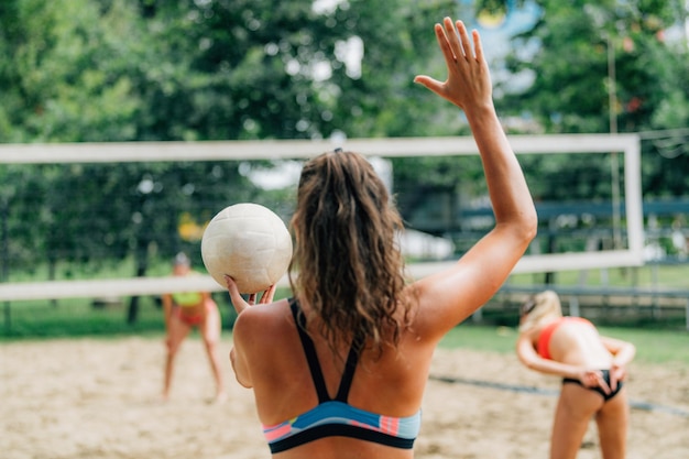 Vrouwelijke strandvolleybalspeler die de bal bedient