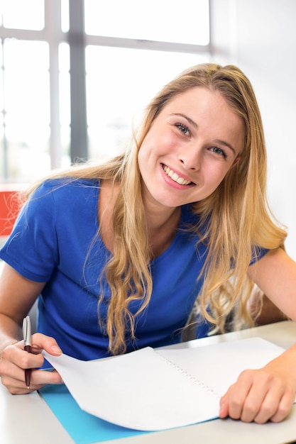 Vrouwelijke student het schrijven van notities in de klas