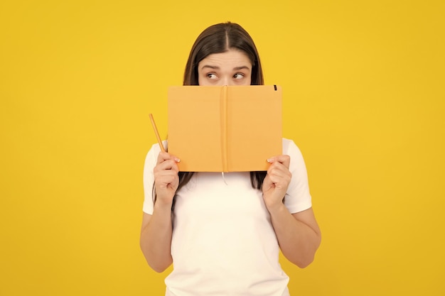 Vrouwelijke student houdt boeken geïsoleerd op gele achtergrond in studio Engels taalschoolonderwijs