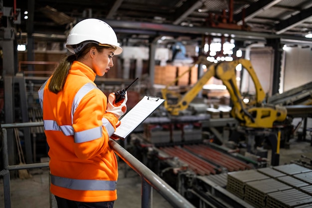 Vrouwelijke supervisor die productielijn in productiefabriek controleert;