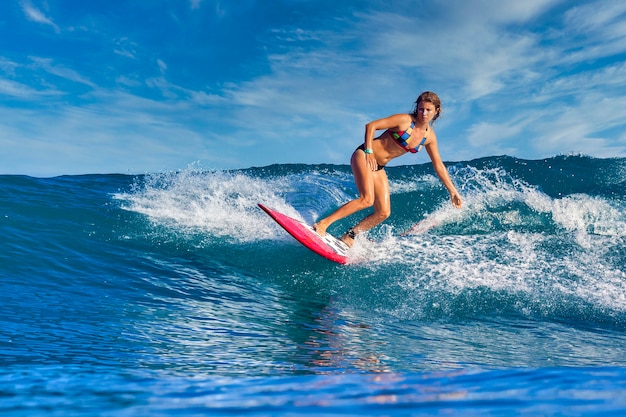 Vrouwelijke surfer op een blauwe golf op zonnige dag