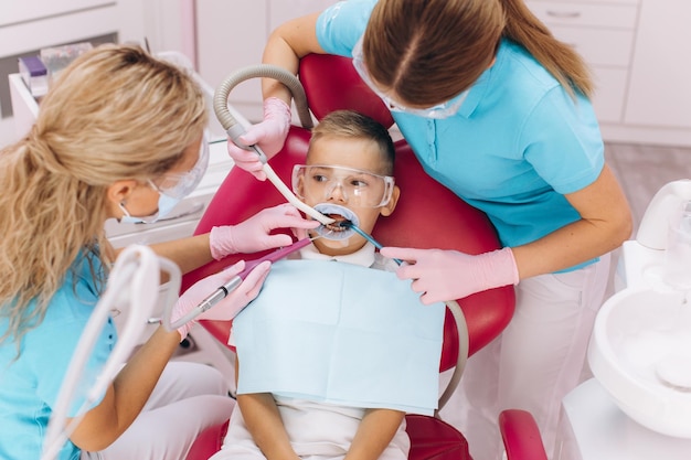 Vrouwelijke tandarts behandelt jongenstanden in tandheelkundige kliniek