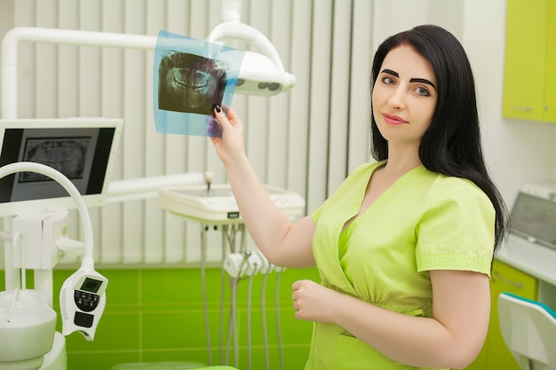 Vrouwelijke tandarts die in tandbureau geduldige tanden onderzoeken