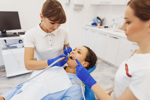 Vrouwelijke tandarts en assistent die tandheelkundige procedures verzorgt voor de tanden van de klant in de medische tandheelkundekamer