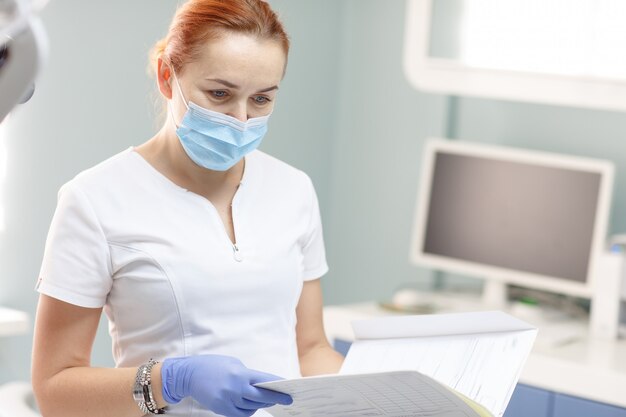 Vrouwelijke tandarts met geduldig meisje die op tandkliniekkantoor spreken