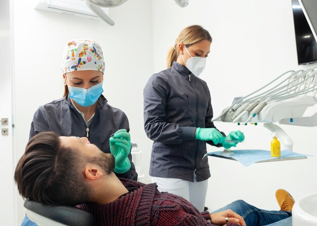 Vrouwelijke tandarts onderzoekt een mannelijke patiënt in een tandartspraktijk