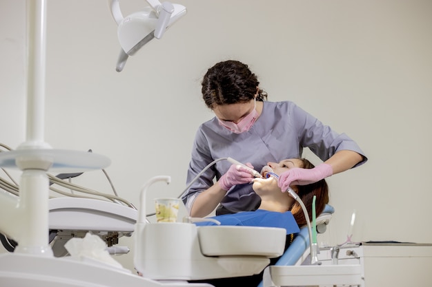 Vrouwelijke tandarts patiënt tanden controleren op tandheelkundige kliniek kantoor. geneeskunde, tandheelkunde concept. tandheelkundige apparatuur.