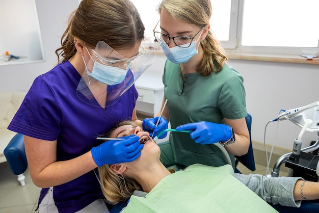 Vrouwelijke tandarts professioneel onderzoek van de mondholte van de patiënt