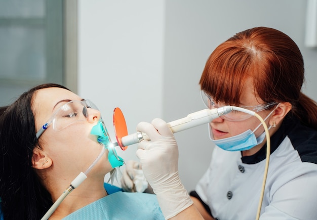 Vrouwelijke tandarts werkt in moderne stomatologie kliniek.