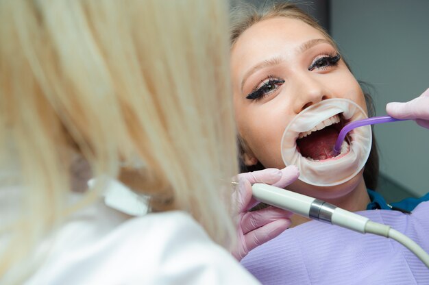 Vrouwelijke tandartsen die patiënt in de kliniek behandelen.