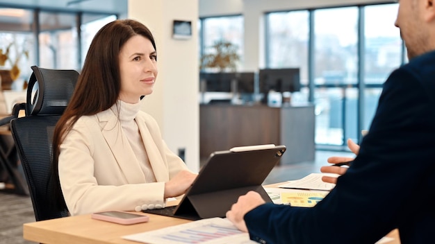 Vrouwelijke teamleider die zakelijke aangelegenheden bespreekt met een medewerker in een kantoor