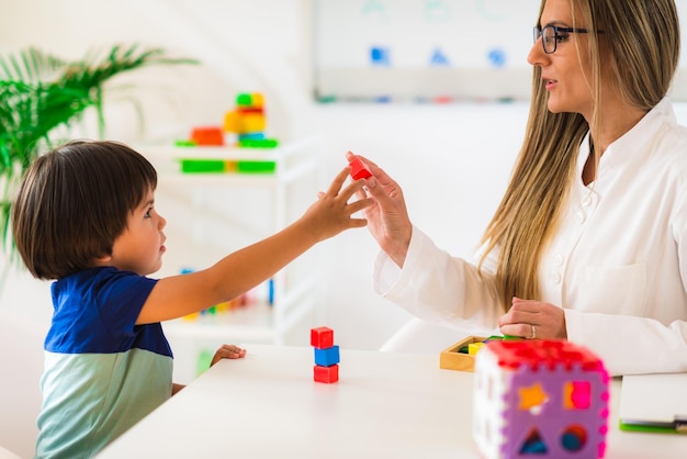 Vrouwelijke therapeut speelt met jongen aan tafel in de kamer