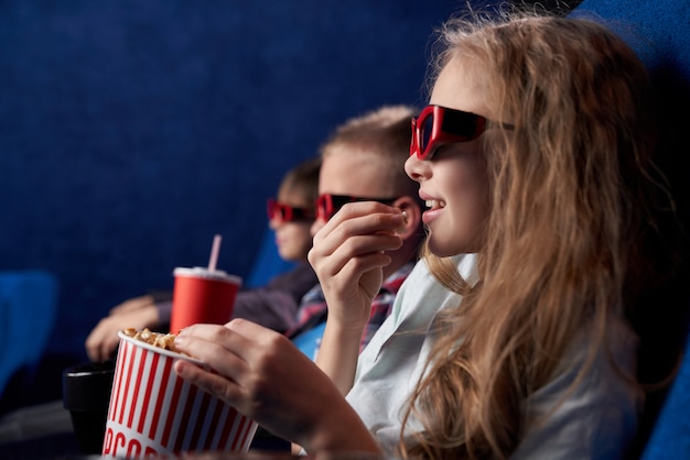 Vrouwelijke tiener in 3d glazen die met vrienden in bioskoop rusten