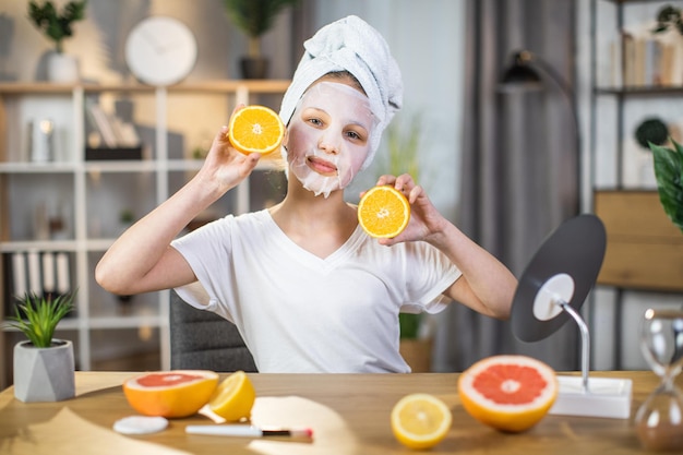 Vrouwelijke tiener met masker op gezicht met plakjes sinaasappelen