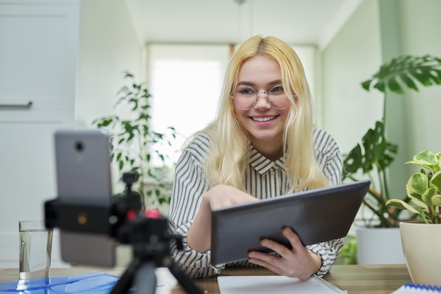 Foto vrouwelijke tiener student praten kijken naar smartphone webcam met behulp van digitale tablet