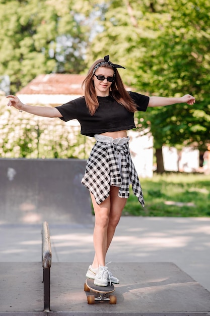 Vrouwelijke tienerschaatser die op het skateboard in het skatepark rijdt
