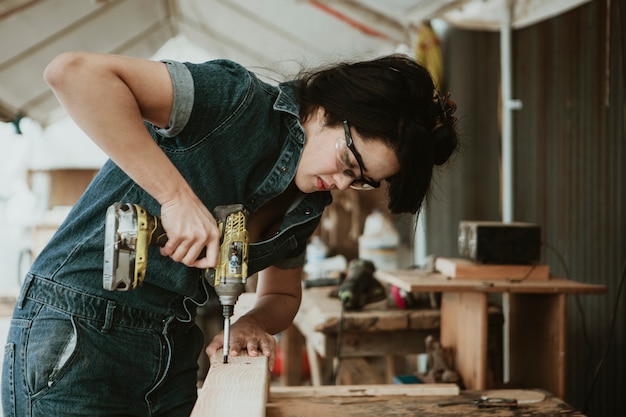 Vrouwelijke timmerman die een hout boort