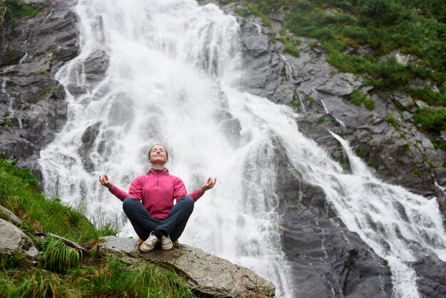 Vrouwelijke toerist die mooie waterval in de bergen waarneemt