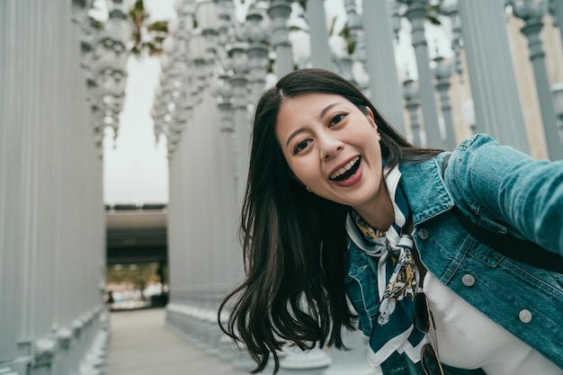 vrouwelijke toerist die selfie neemt voor het Los Angeles County Museum of Art met een aantrekkelijke glimlach