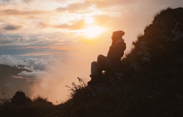 Vrouwelijke toerist met een rugzak in de herfst op de berg met uitgestrekte armen verwelkomt bewondert de zonsondergang