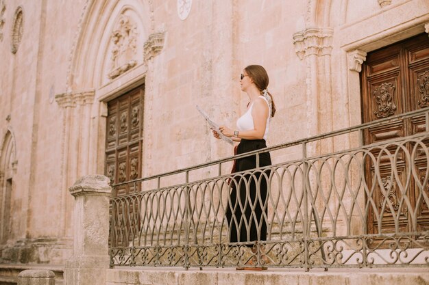 Vrouwelijke toerist met een stadsplattegrond bij de kerk San Francesco d'Assisi in Ostuni, Italië