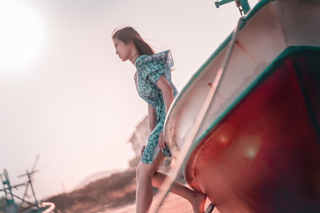 Foto vrouwelijke toerist zit op een boot op een strandzonsondergang voor zomervakantieconcept